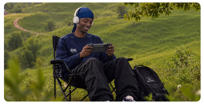 Un joueur assis dans l’herbe joue avec la manette Osyn Pro.
